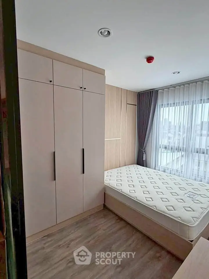 Modern bedroom with large window and built-in wardrobe in a stylish apartment.