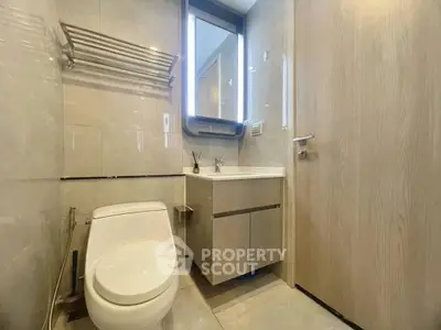 Modern bathroom with sleek fixtures and elegant lighting, featuring a compact design and stylish mirror.