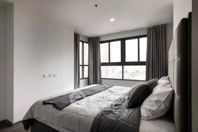 Modern bedroom with large windows and stylish decor in a high-rise apartment.
