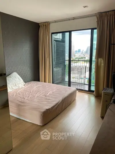 Modern bedroom with city view and balcony access in a stylish apartment.