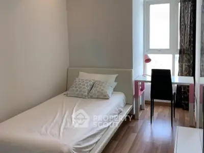 Cozy bedroom with single bed, study desk, and large window for natural light.