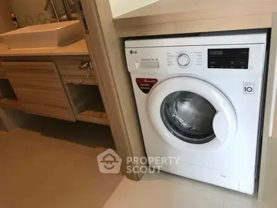 Modern bathroom with integrated washing machine and stylish wooden cabinetry.