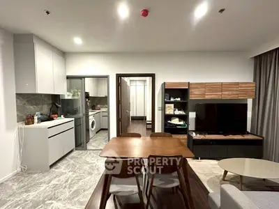 Modern open-layout living room with dining area and kitchen, featuring sleek furniture and contemporary design.