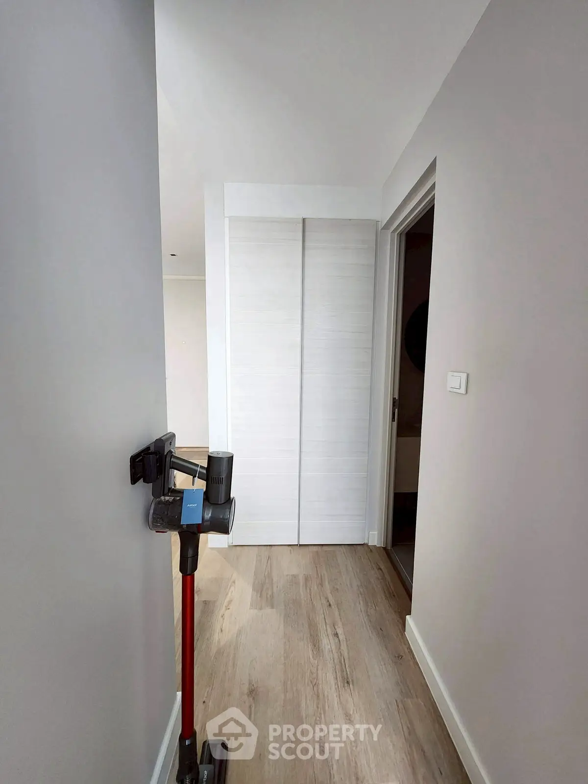 Modern hallway with sleek vacuum cleaner and wooden flooring