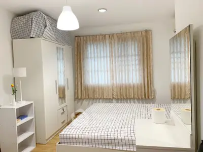 Bright and inviting bedroom with large window, crisp white bedding, and ample storage, perfect for a restful retreat in a modern home.