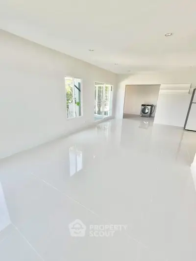 Spacious modern living room with glossy white tiles and large windows