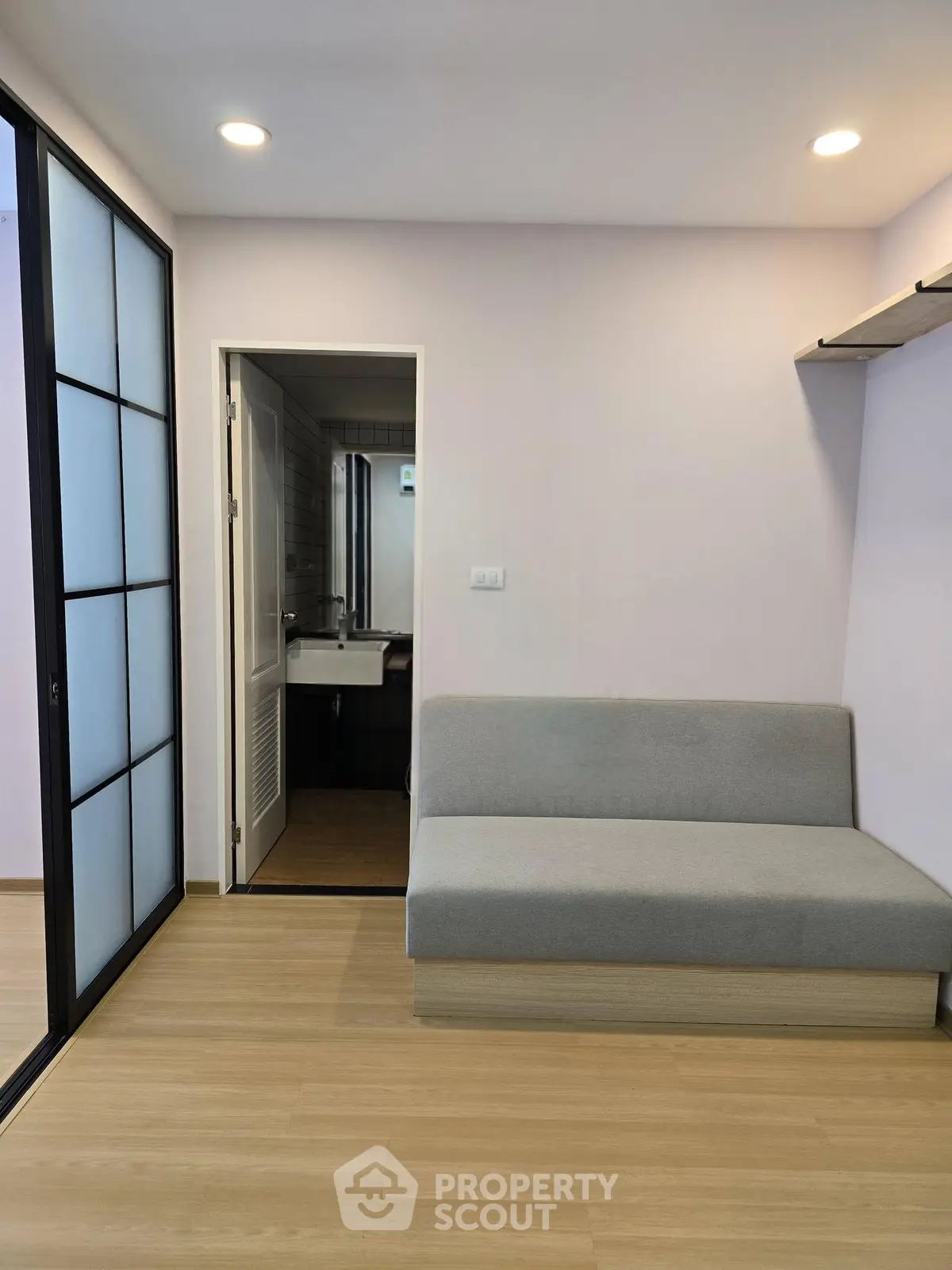 Modern minimalist living room with sleek design and cozy sofa adjacent to bathroom entrance.