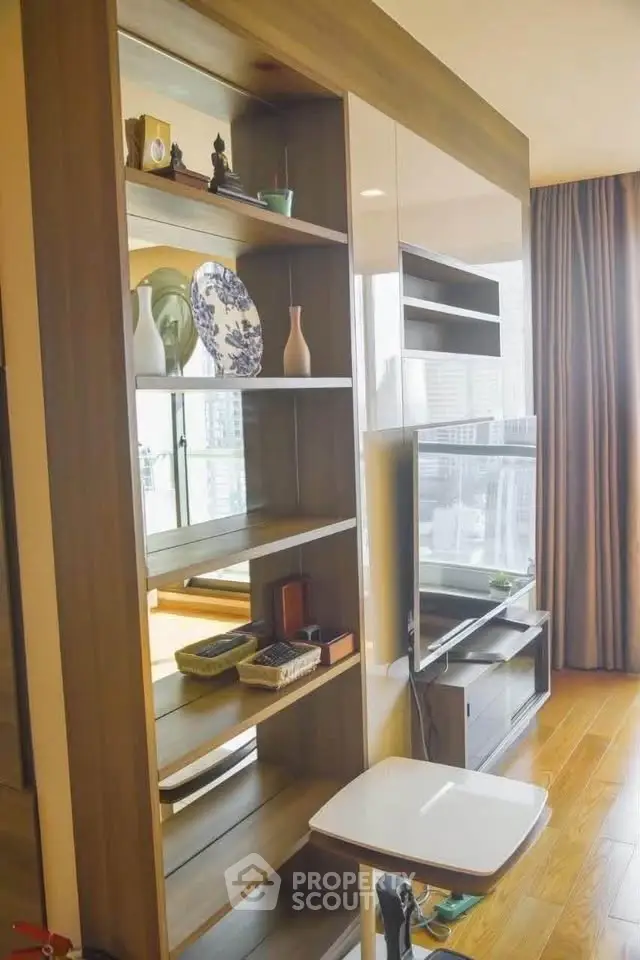 Modern living room with stylish shelving and TV unit, featuring floor-to-ceiling windows and elegant decor.