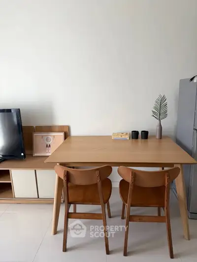 Modern dining area with wooden table and chairs, minimalist decor, and sleek TV stand.