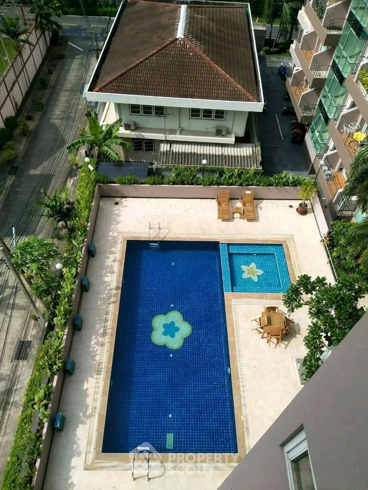 Stunning aerial view of a luxurious residential pool area with elegant seating and lush greenery.