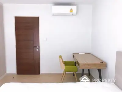 Modern study room with wooden desk and chair, featuring minimalist design and air conditioning.