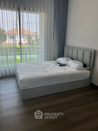 Spacious bedroom with modern bed and large window offering scenic views.