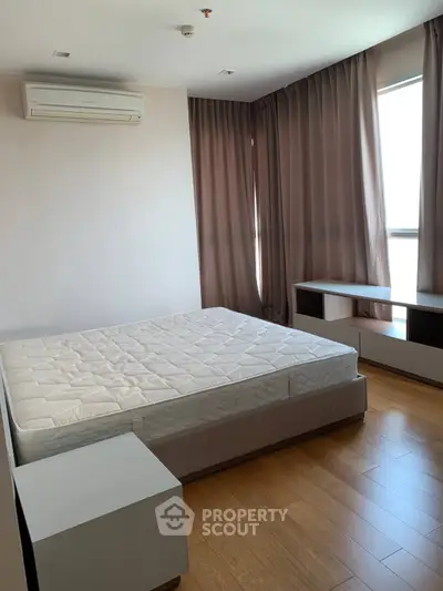 Spacious bedroom with natural light and modern furnishings in a stylish apartment.