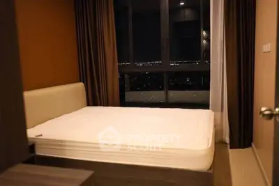 Cozy bedroom with city view, featuring modern furnishings and large window for natural light.