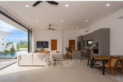 Luxurious open-plan living room with pool view and modern kitchen in a tropical villa.