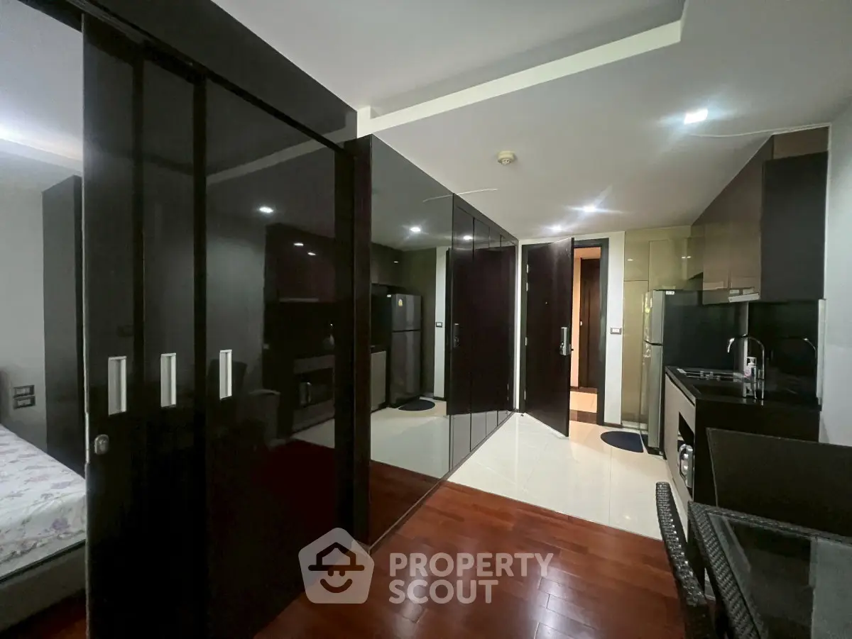 Modern studio apartment with sleek kitchen and mirrored wardrobe doors.