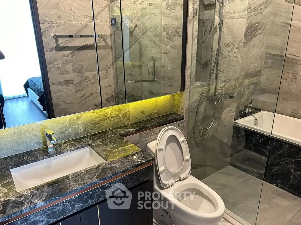 Luxurious modern bathroom with marble finishes and glass shower enclosure.