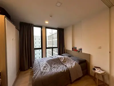 Cozy bedroom with large window and modern furnishings in urban apartment