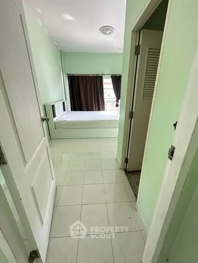 Cozy bedroom with natural light and minimalist design, featuring a comfortable bed and tiled flooring.