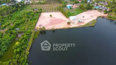 Aerial view of a serene lakeside property with lush greenery and development potential.