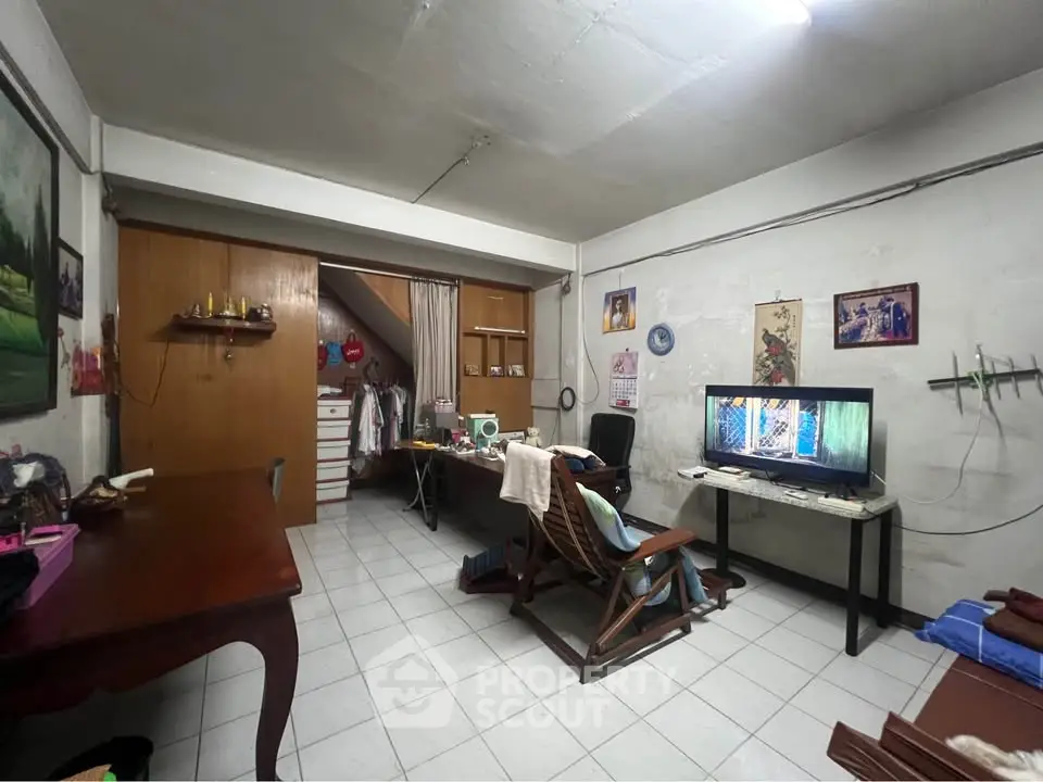 Cozy living room with TV, wooden furniture, and decorative wall art in a compact space.