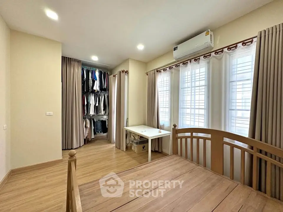 Spacious bedroom with wooden flooring, large windows, and built-in closet in modern home.