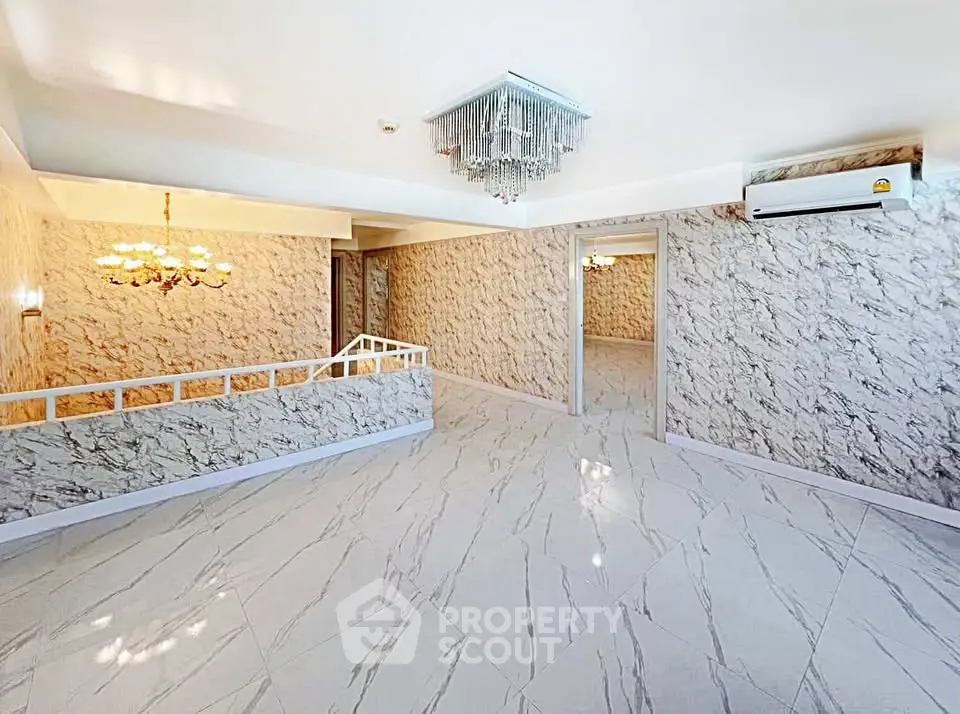 Spacious living room with elegant chandelier and marble flooring in a luxurious home.