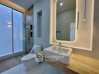 Modern bathroom with sleek design, featuring a large mirror and glass shower enclosure.