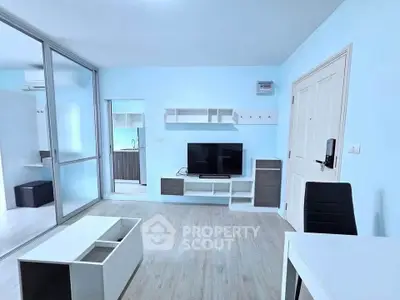 Modern living room with sleek furniture and light blue walls, featuring a TV and glass partition.