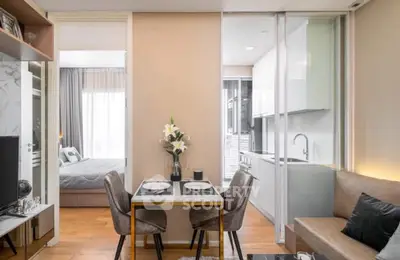 Modern open-plan living and dining area with sleek kitchen and cozy bedroom view.