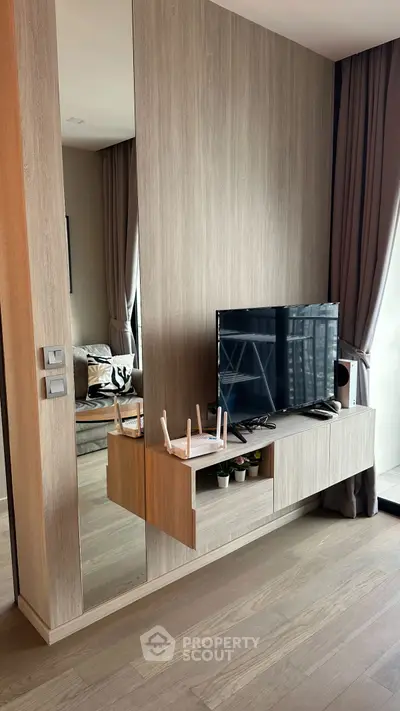 Modern living room with sleek TV unit and large mirror, featuring elegant curtains and wooden flooring.