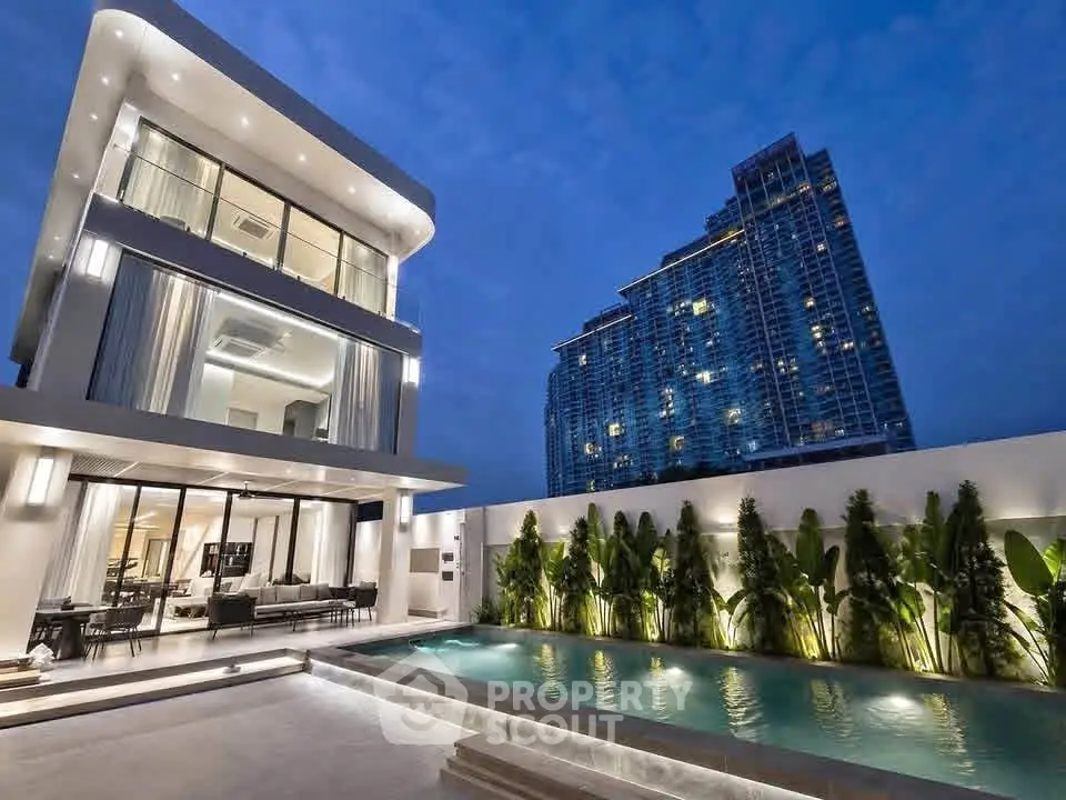 Luxurious modern villa with illuminated pool and stunning cityscape view at dusk.