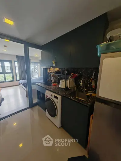 Modern kitchen with sleek appliances and open layout leading to a bright bedroom.