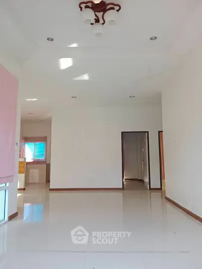 Spacious empty living room with white tiles and modern lighting, ready for customization.