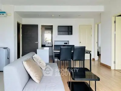 Modern living room with sleek furniture and open layout, featuring a cozy sofa and dining area.