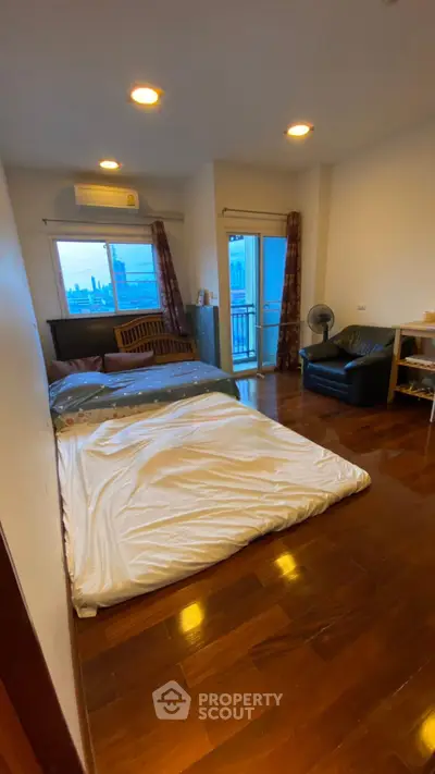 Cozy bedroom with wooden flooring and balcony access in modern apartment