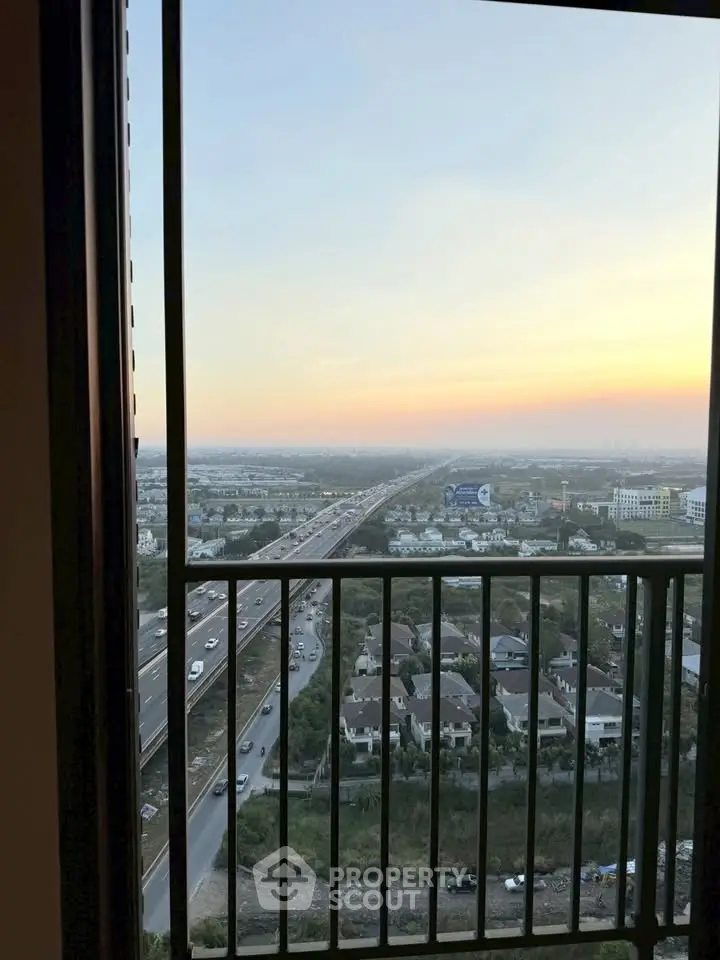 Stunning high-rise balcony view overlooking cityscape and highway at sunset.