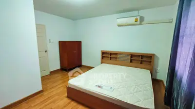 Spacious bedroom with wooden flooring and air conditioning in modern apartment