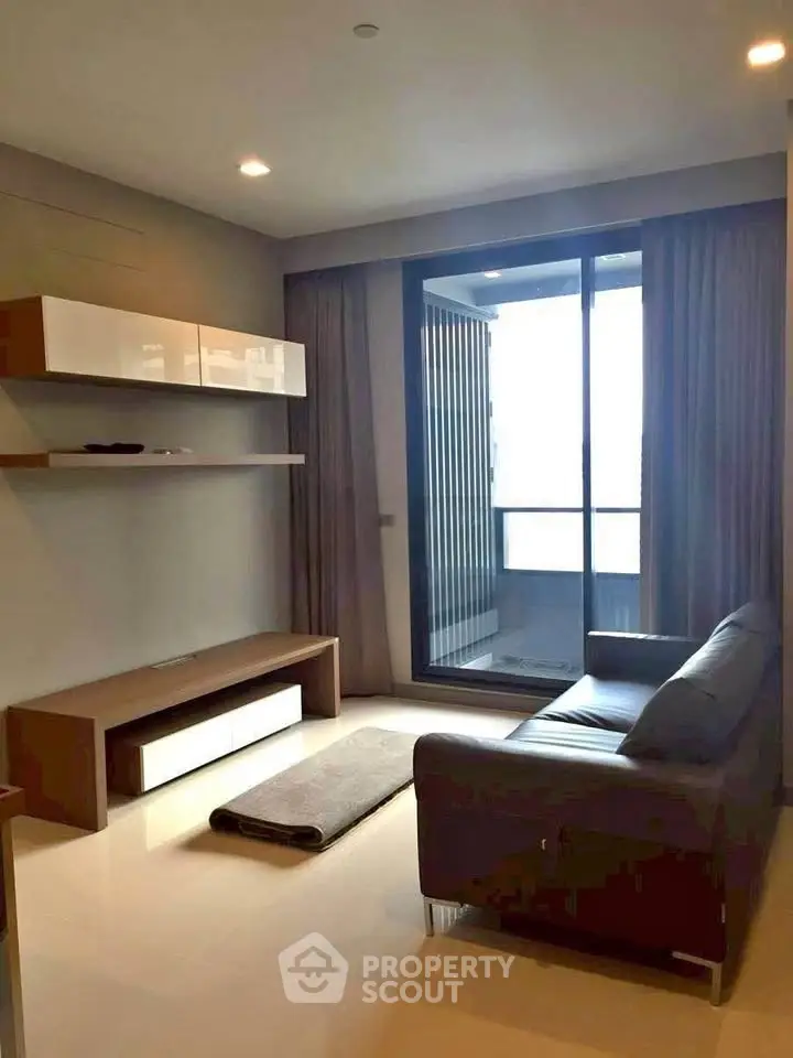 Modern living room with sleek furniture and large window leading to a balcony, offering a cozy and inviting atmosphere.