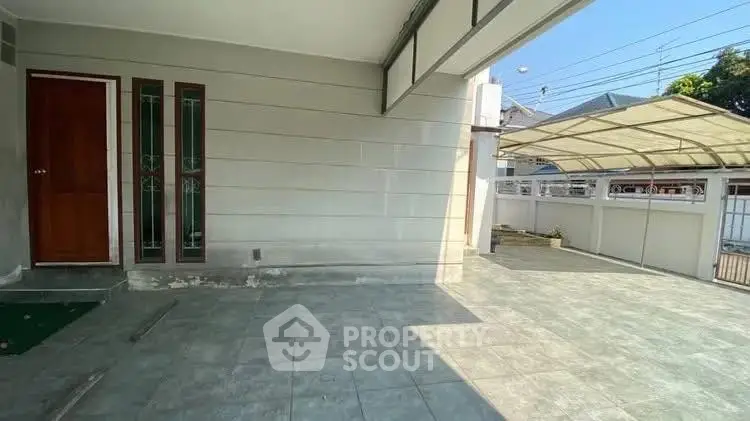 Spacious residential entrance with tiled flooring and covered parking area.