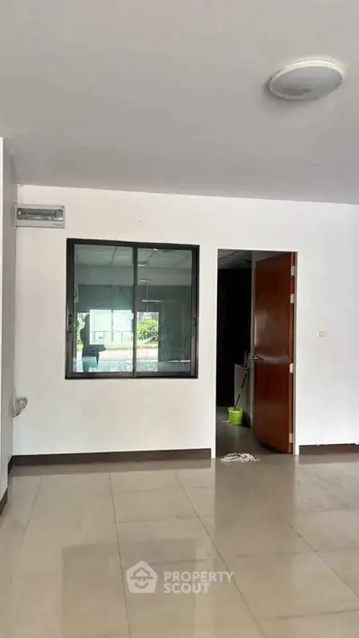 Spacious interior with tiled flooring and large window, ideal for customization.