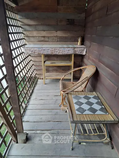 Charming rustic balcony with wooden walls and chess table, perfect for relaxation.