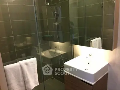 Modern bathroom with glass shower and sleek vanity in stylish apartment.