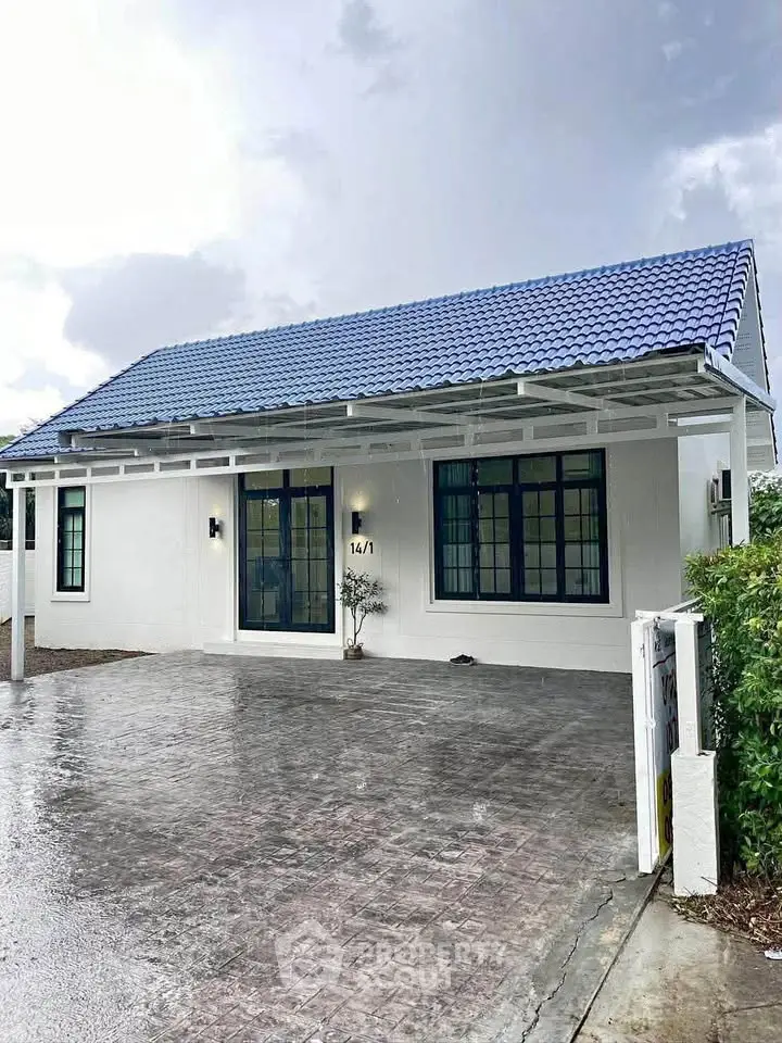 Charming single-story home with blue roof and spacious driveway, perfect for modern family living.