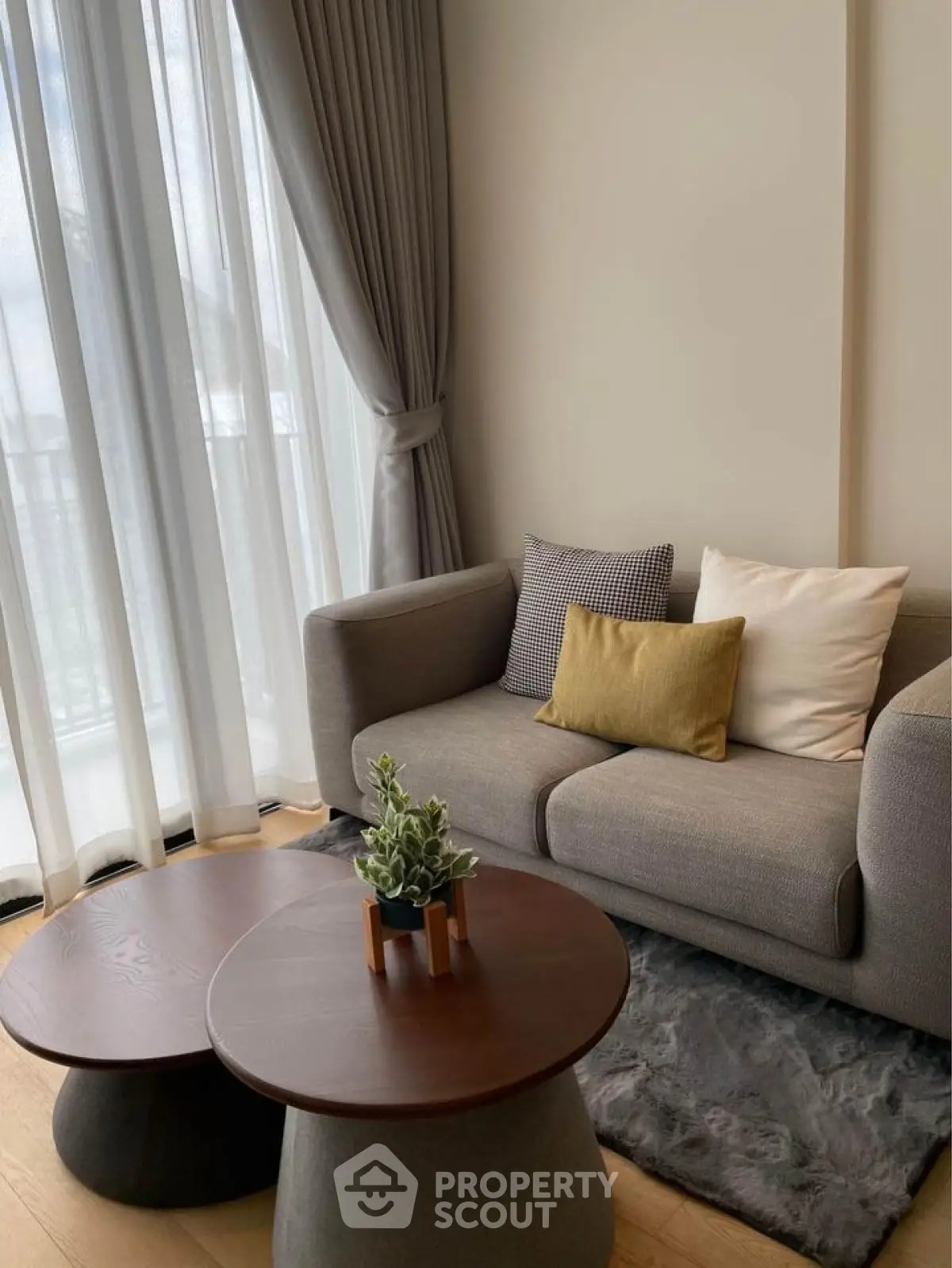 Cozy living room with modern sofa, stylish coffee tables, and elegant curtains in a bright, inviting space.