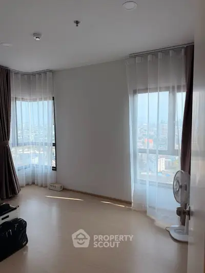 Spacious room with large windows offering panoramic city views, perfect for a bright and airy living space.