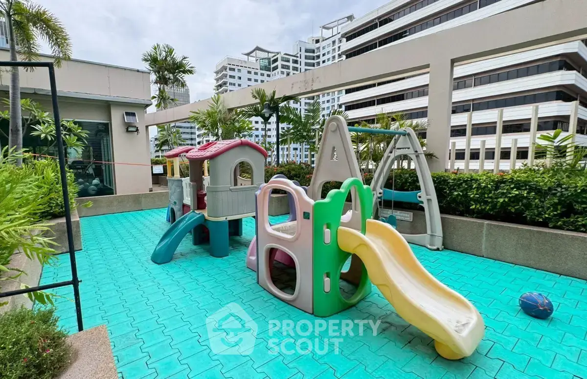 Modern residential building with vibrant rooftop playground featuring slides and climbing structures.