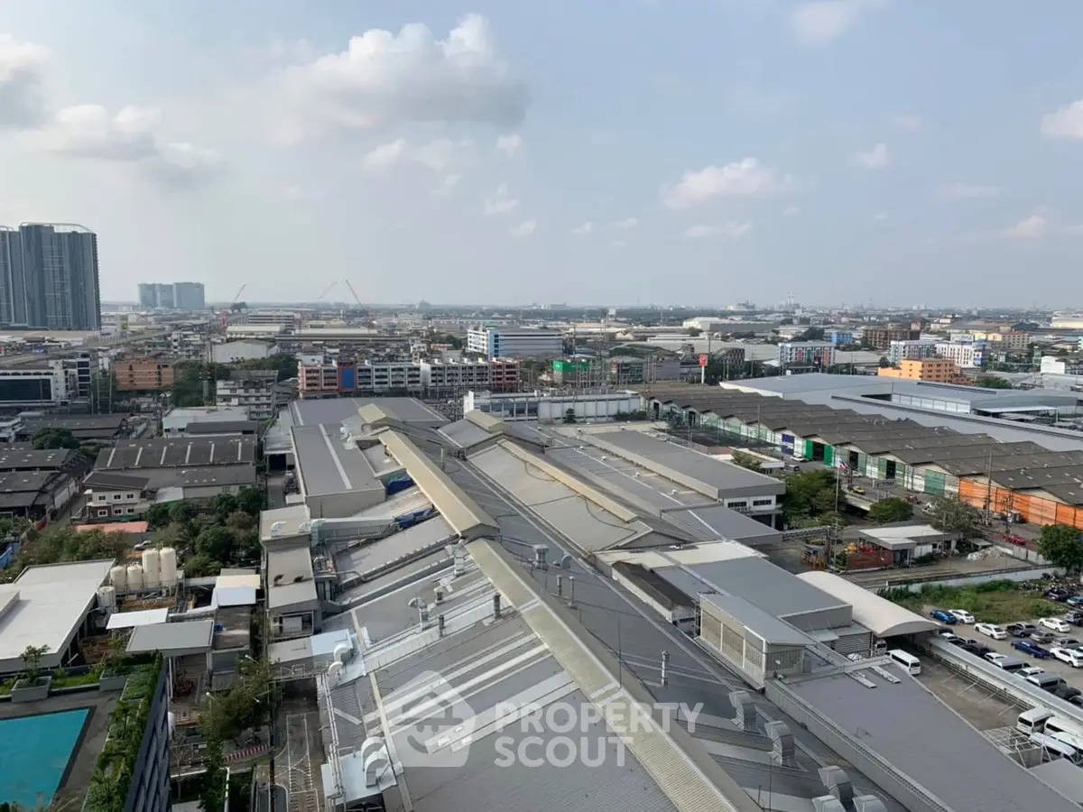 Panoramic cityscape view showcasing industrial and residential buildings under a cloudy sky.