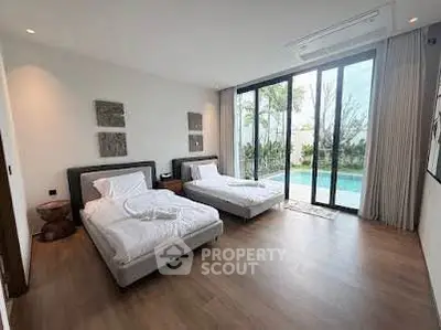 Luxurious bedroom with pool view and modern decor, featuring twin beds and floor-to-ceiling windows.