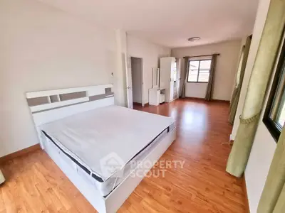 Spacious bedroom with wooden flooring and large windows for natural light